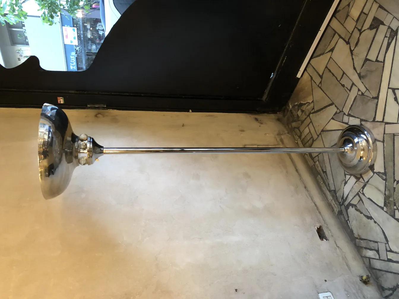 Luminária de pé antiga com base brilhante e cúpula elegante em um ambiente com piso decorativo.