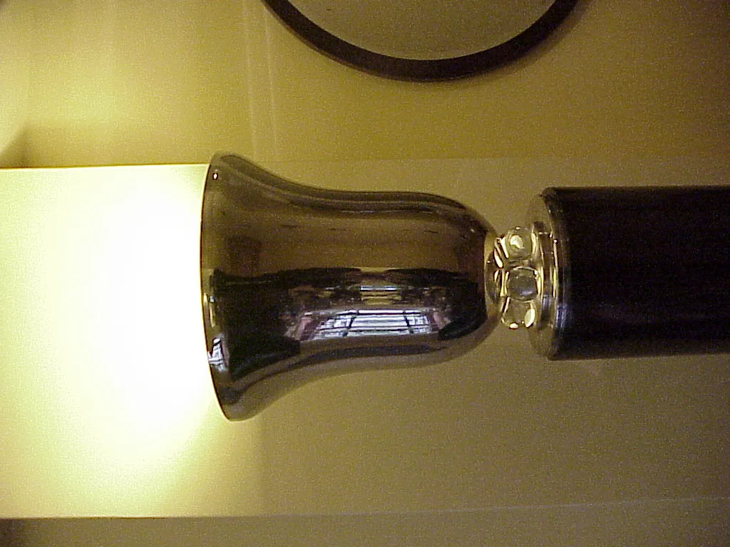 Torchiere ancienne avec base brillante et lumière douce dans une ambiance accueillante.