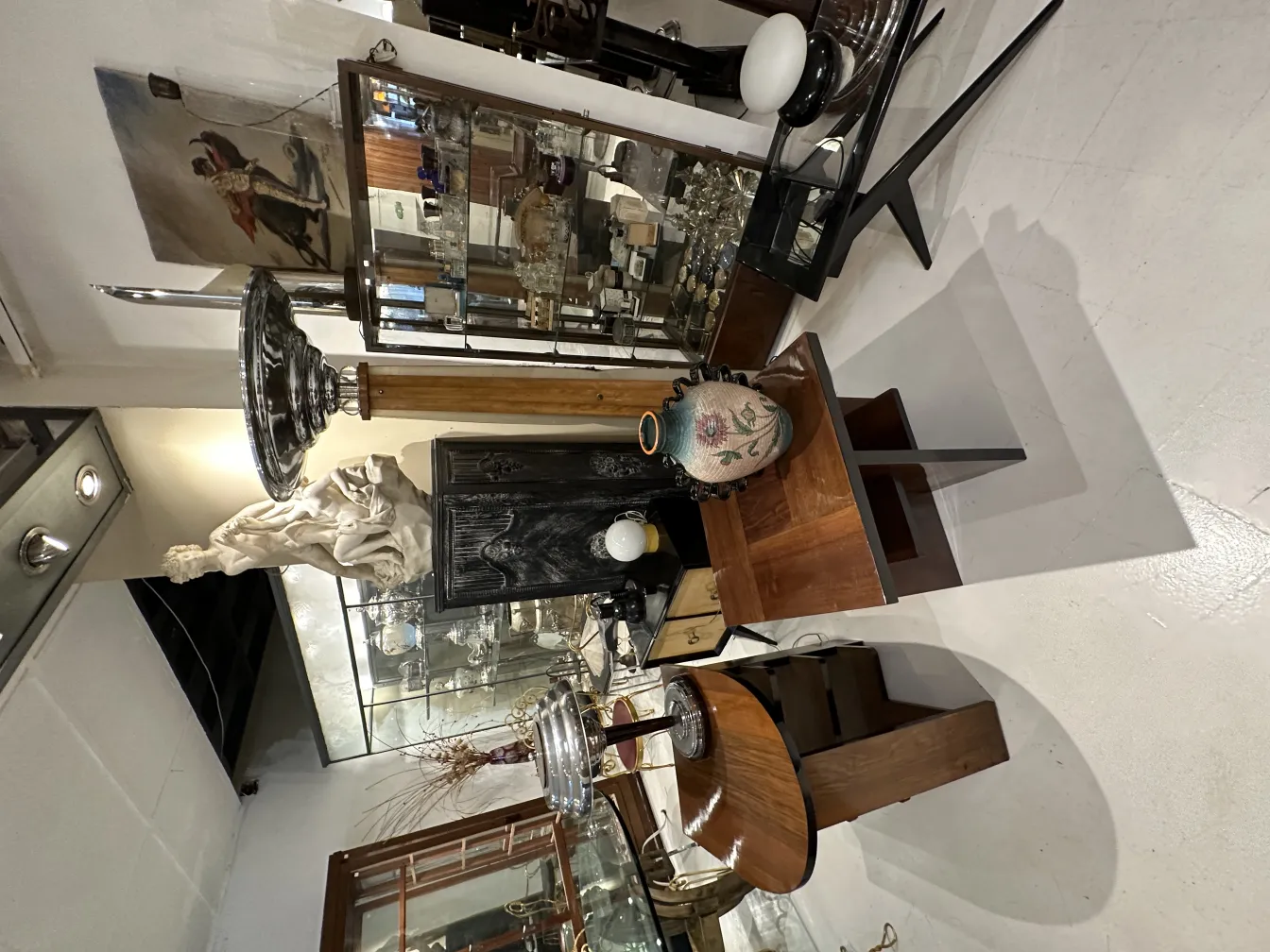 Lámpara de pie antigua con base elegante y pantalla blanca, rodeada de decoraciones vintage.