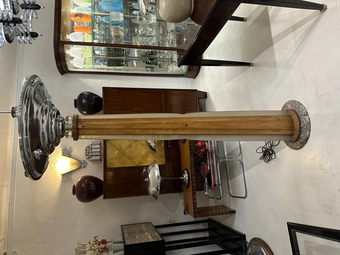 Lámpara de pie antigua con base elegante y pantalla en metal, en un entorno de muebles decorativos.