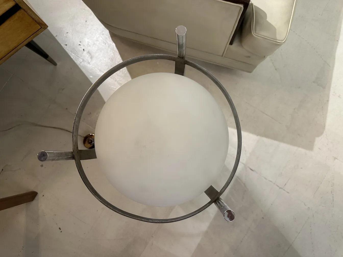 Luminária de pé antiga com esfera branca em um ambiente moderno.