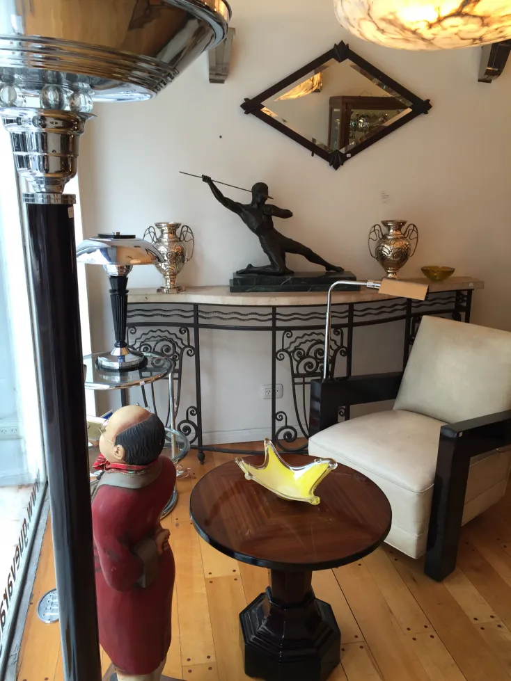 Torchiere ancienne avec une finition brillante, entourée d'antiquités dans un cadre élégant.