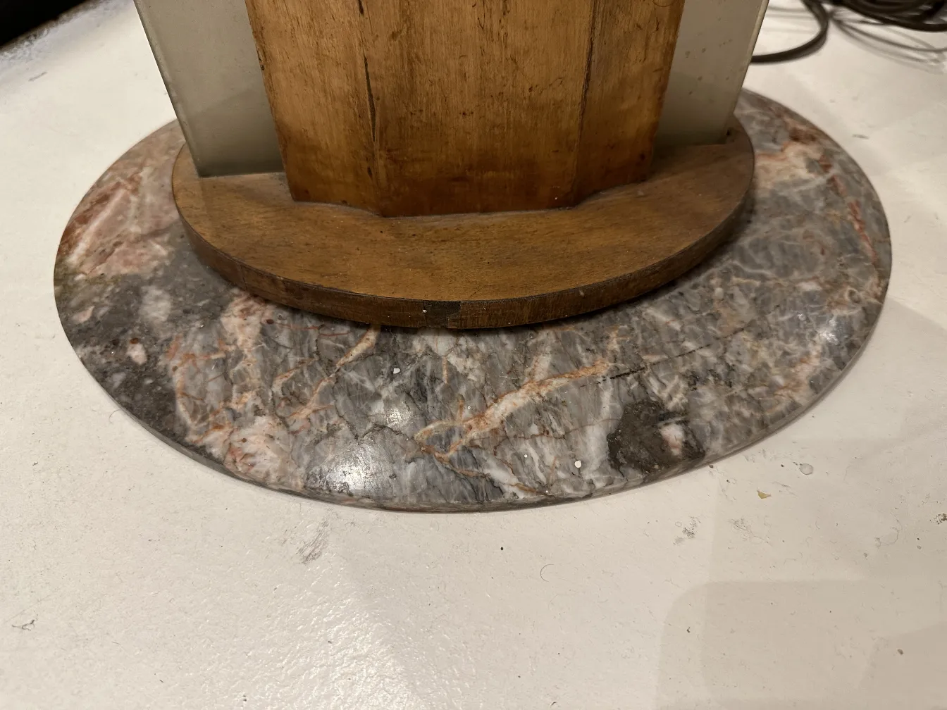 Lampada da terra antica con base in marmo e dettagli in legno, ambientata in un contesto neutro.