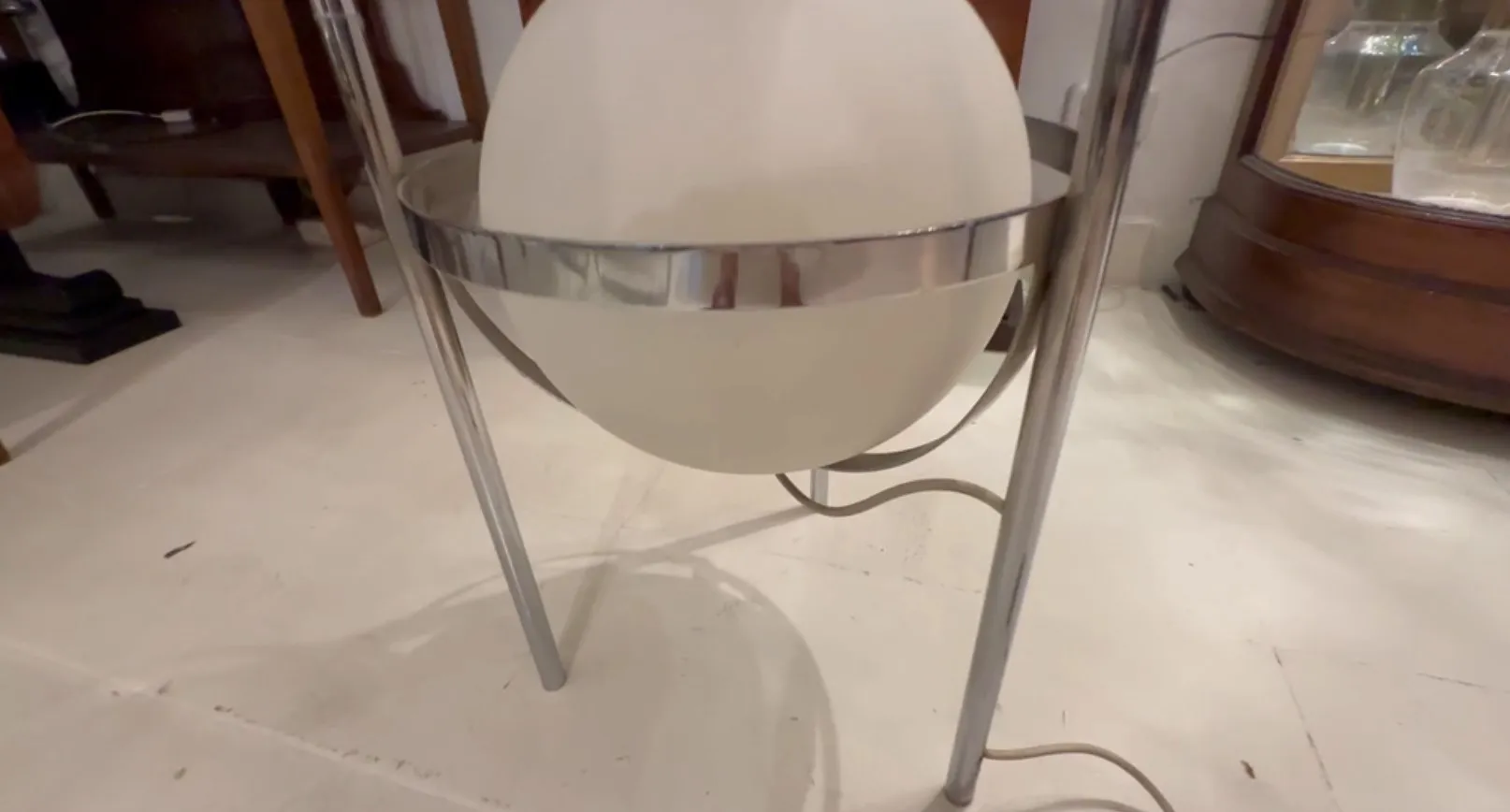 antique floor lamp with shiny finish and white sphere, set in a cozy environment