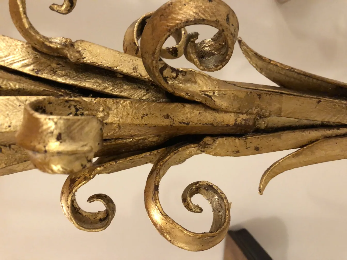 Détail d'une ancienne torchiere avec des touches dorées et des formes élégantes.