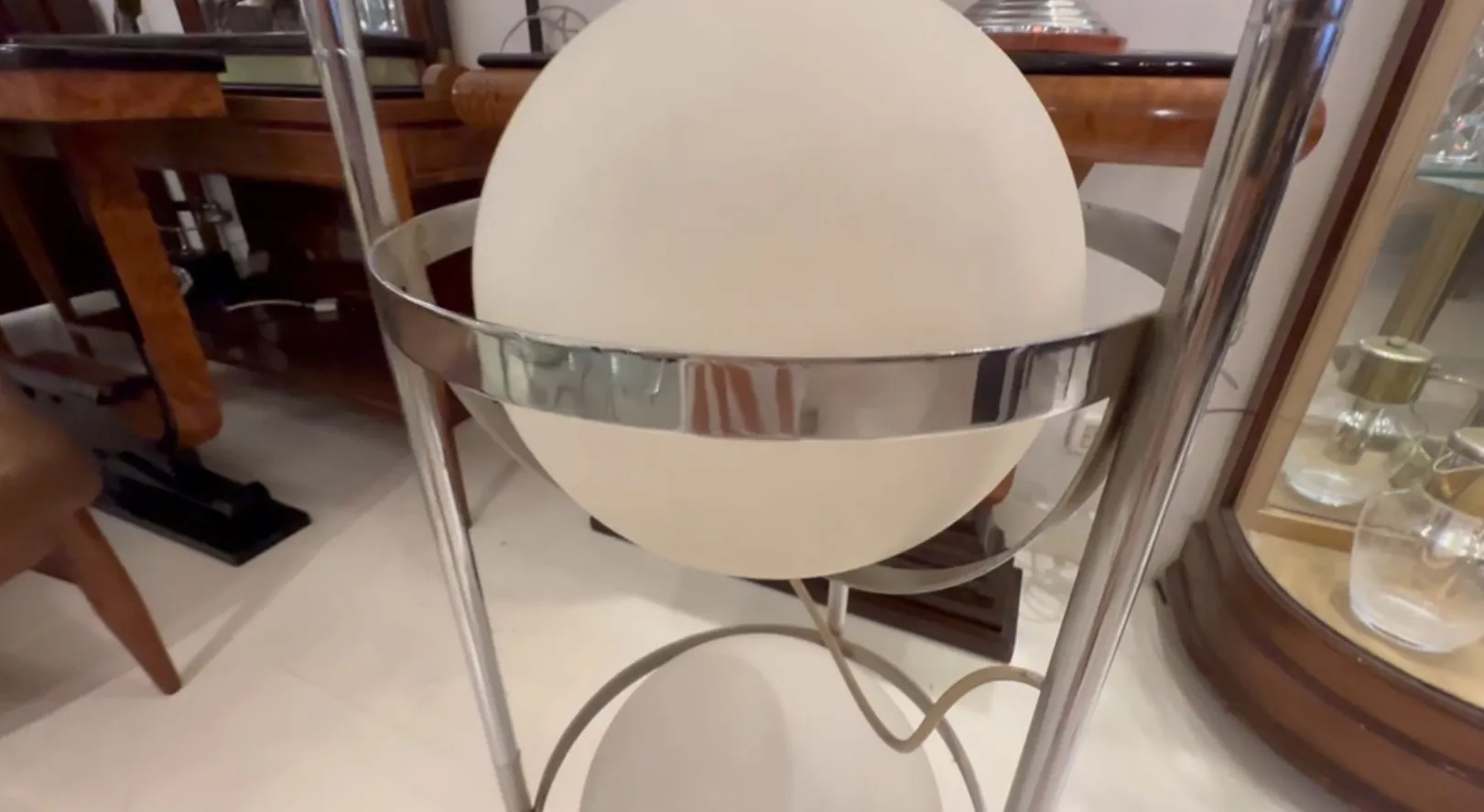 Lampada da terra antica con design orbitale, ambientata in un contesto classico.