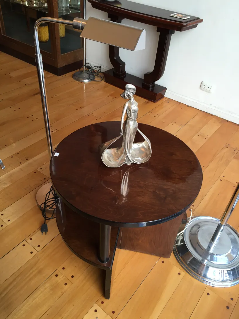 Antique floor lamp with elegant design, featuring a round base and adjustable arms, in a classic setting with a table.