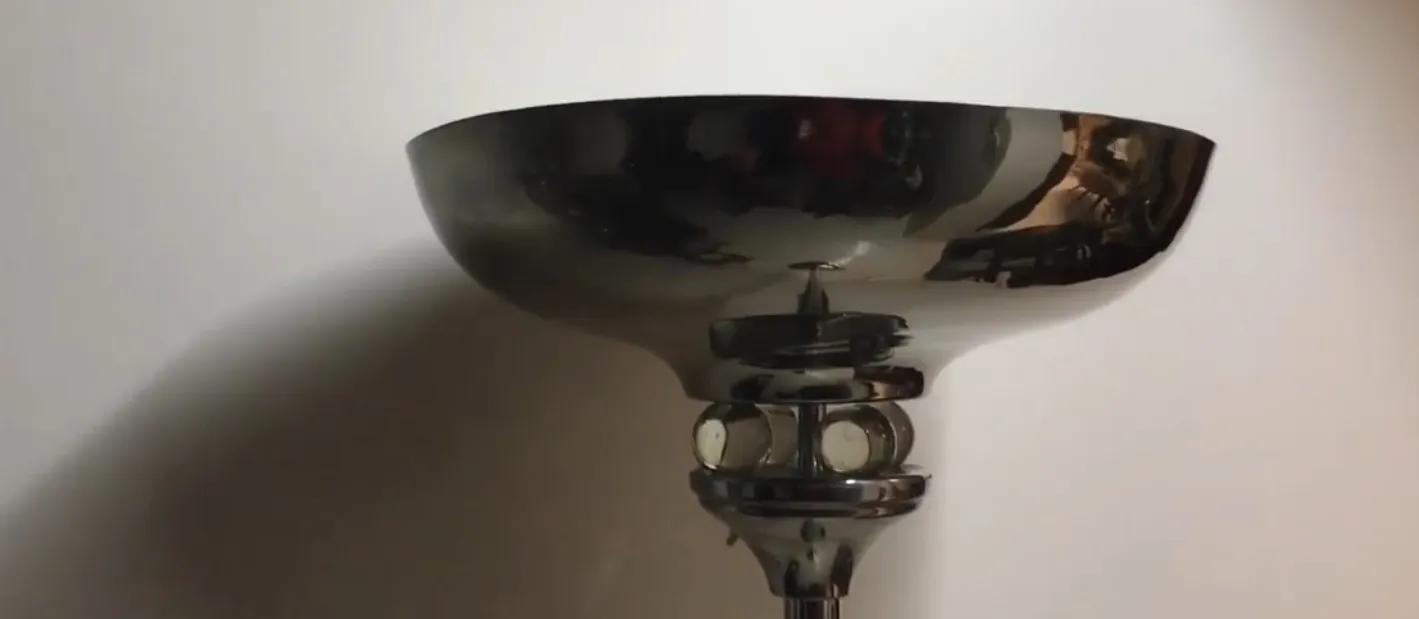 Lámpara de pie antigua con diseño minimalista y cúpula reflectante, en un ambiente acogedor.