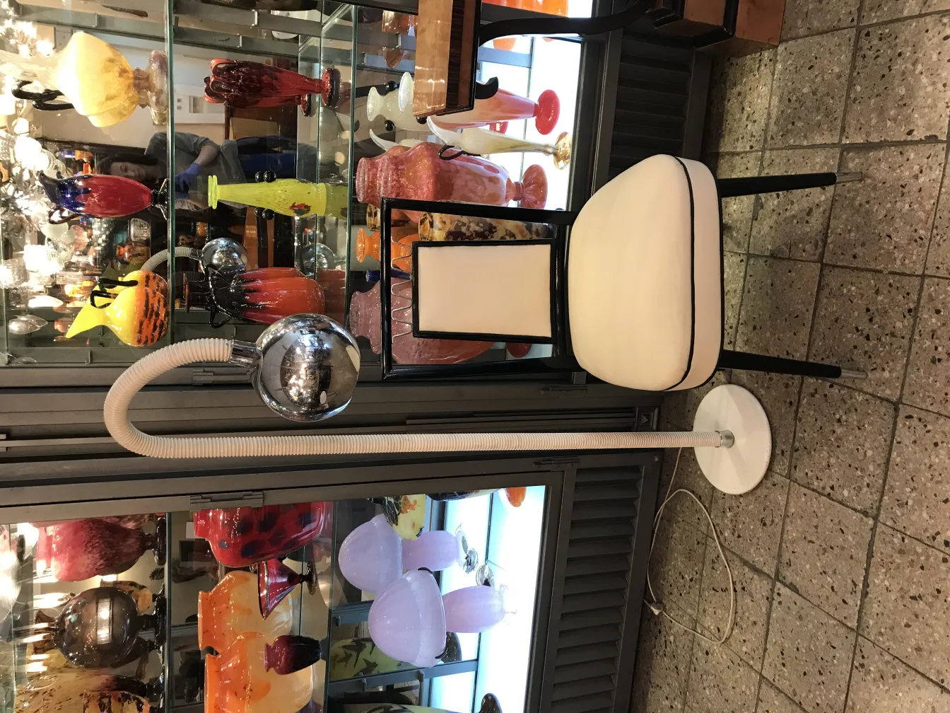 Antike Stehleuchte mit gebogenem Design und weißem Sockel, elegantes Ambiente.