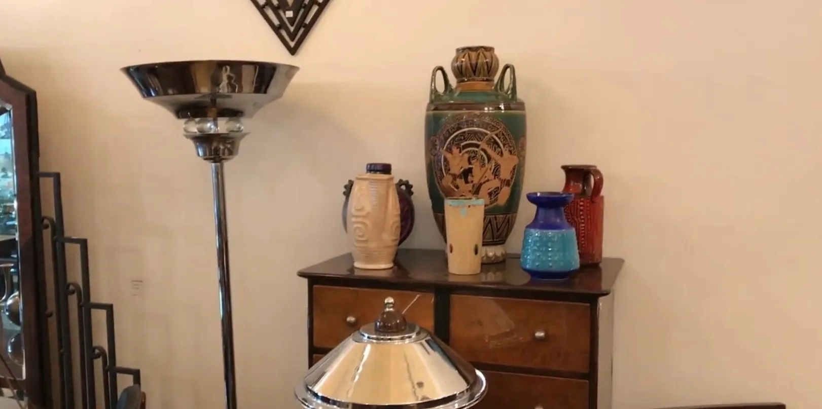 Antique floor lamp with a metal base and classic shade, surrounded by colorful decorative items.