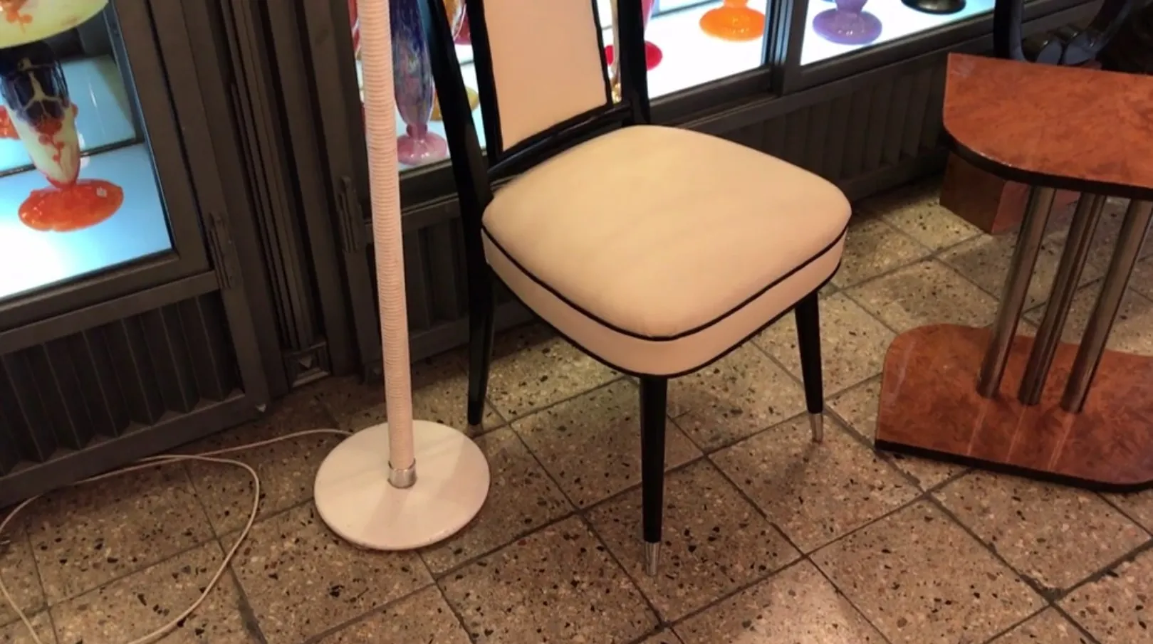 Luminária de pé antiga com base redonda, luz suave, ambiente acolhedor.