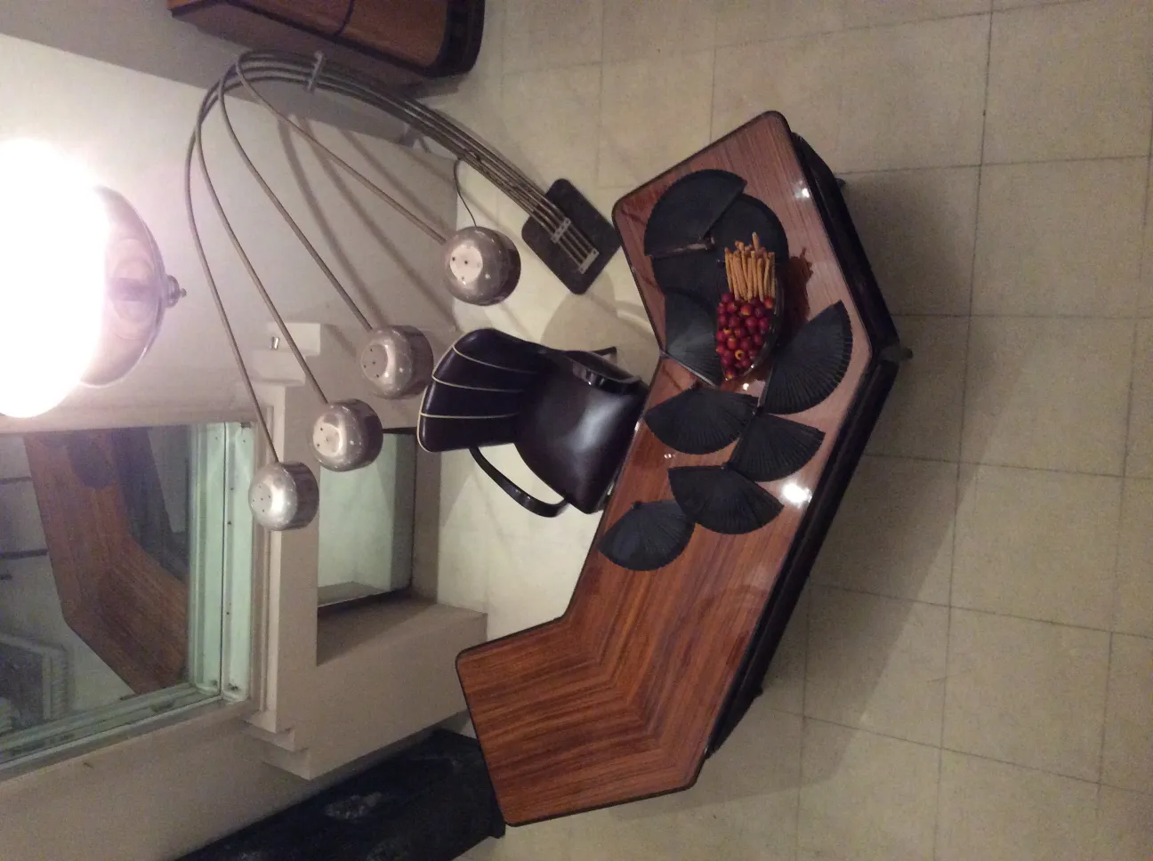 Lampada da terra antica con più luci e design elegante, sedia e tavolo sullo sfondo.