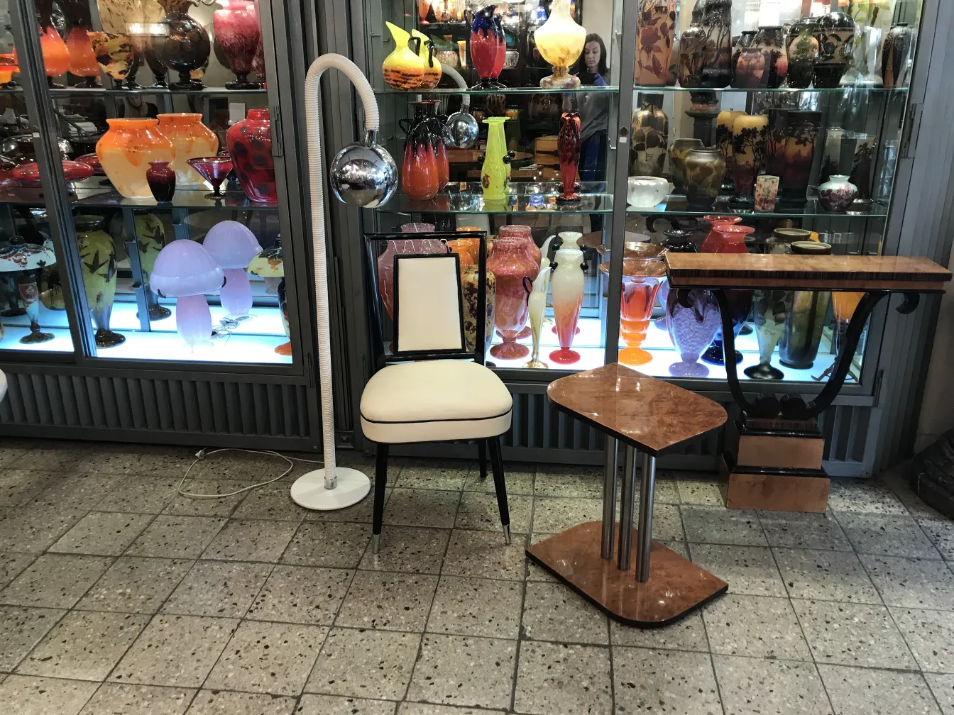 古いフロアランプはミラーボール付きで、ヴィンテージの背景にあります。背景には白い椅子と装飾的なテーブルがあります。