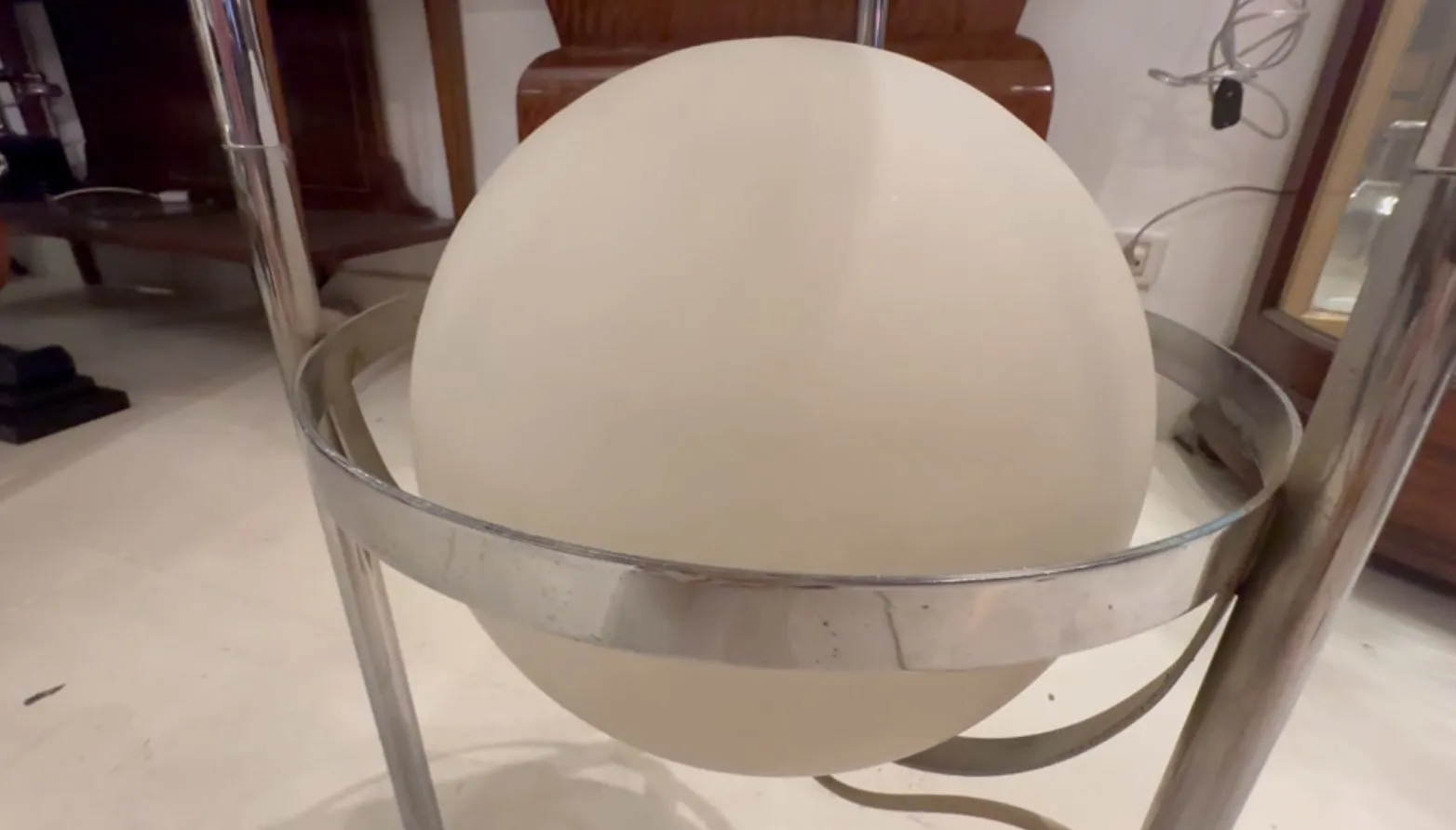 Luminária de pé antiga com globo branco e base metálica em ambiente sofisticado.