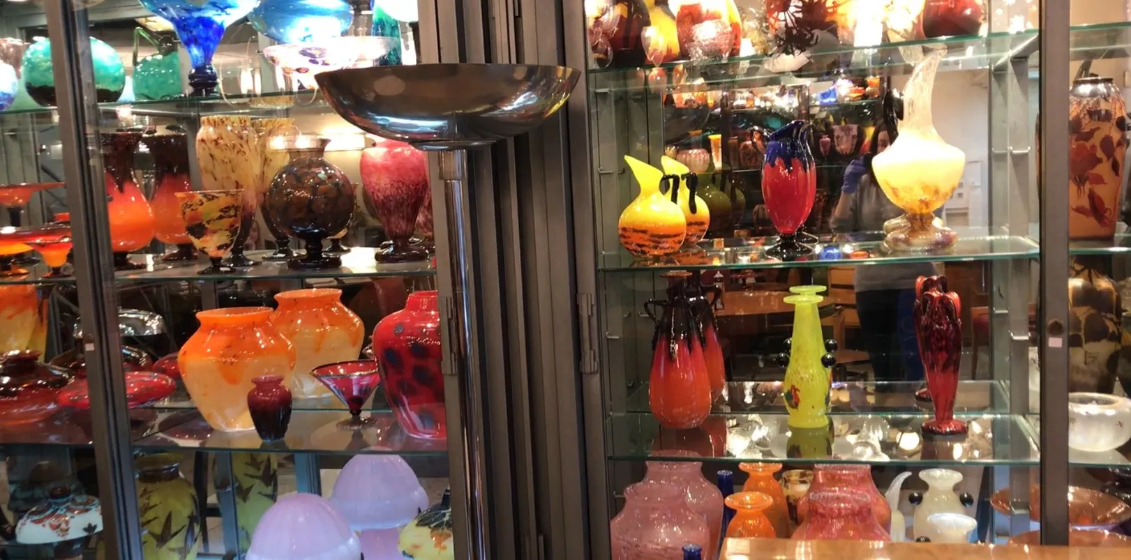 Antique floor lamp amid colorful glass vases