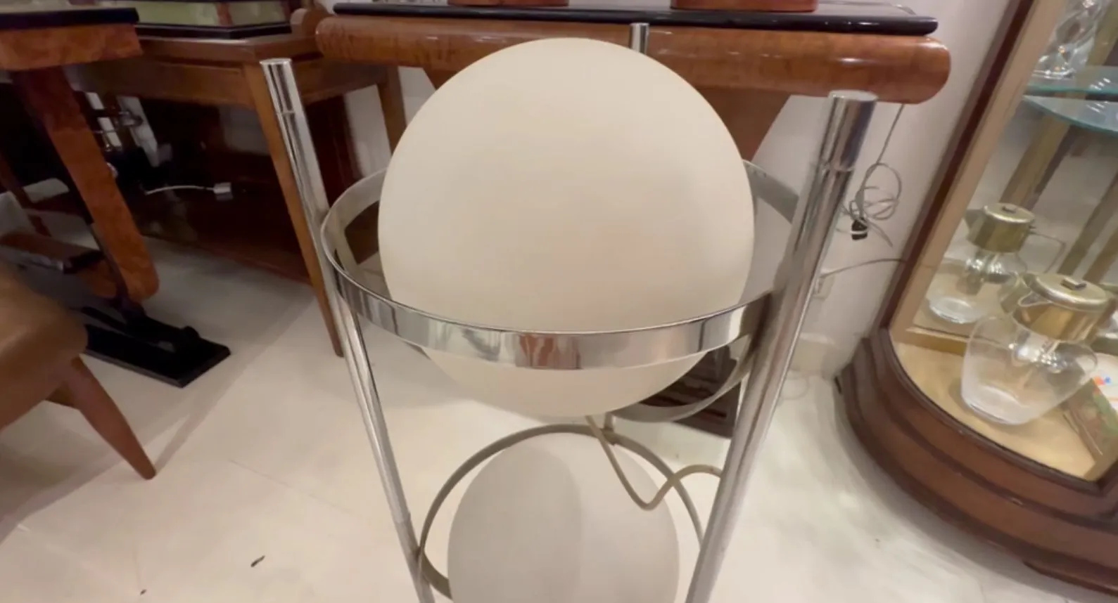 Luminária de pé antiga com design de balcão e luz difusa, cercada por móveis elegantes.