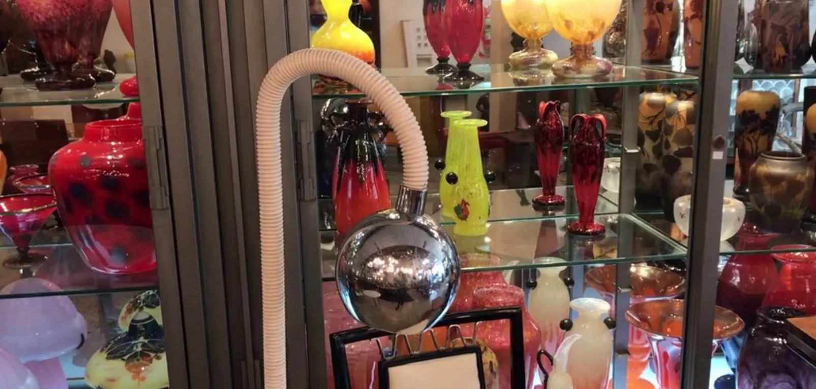 Antique floor lamp with a shiny structure, adorned among other colorful antiques.