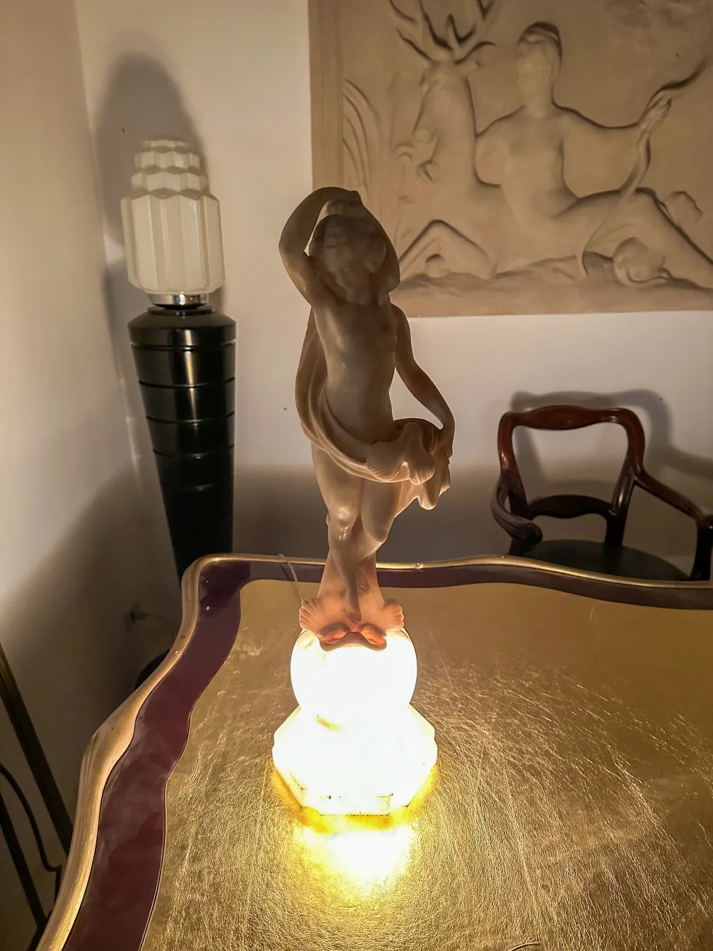 due lampade da terra antiche in un ambiente elegante, una con figura decorativa e l'altra con design moderno