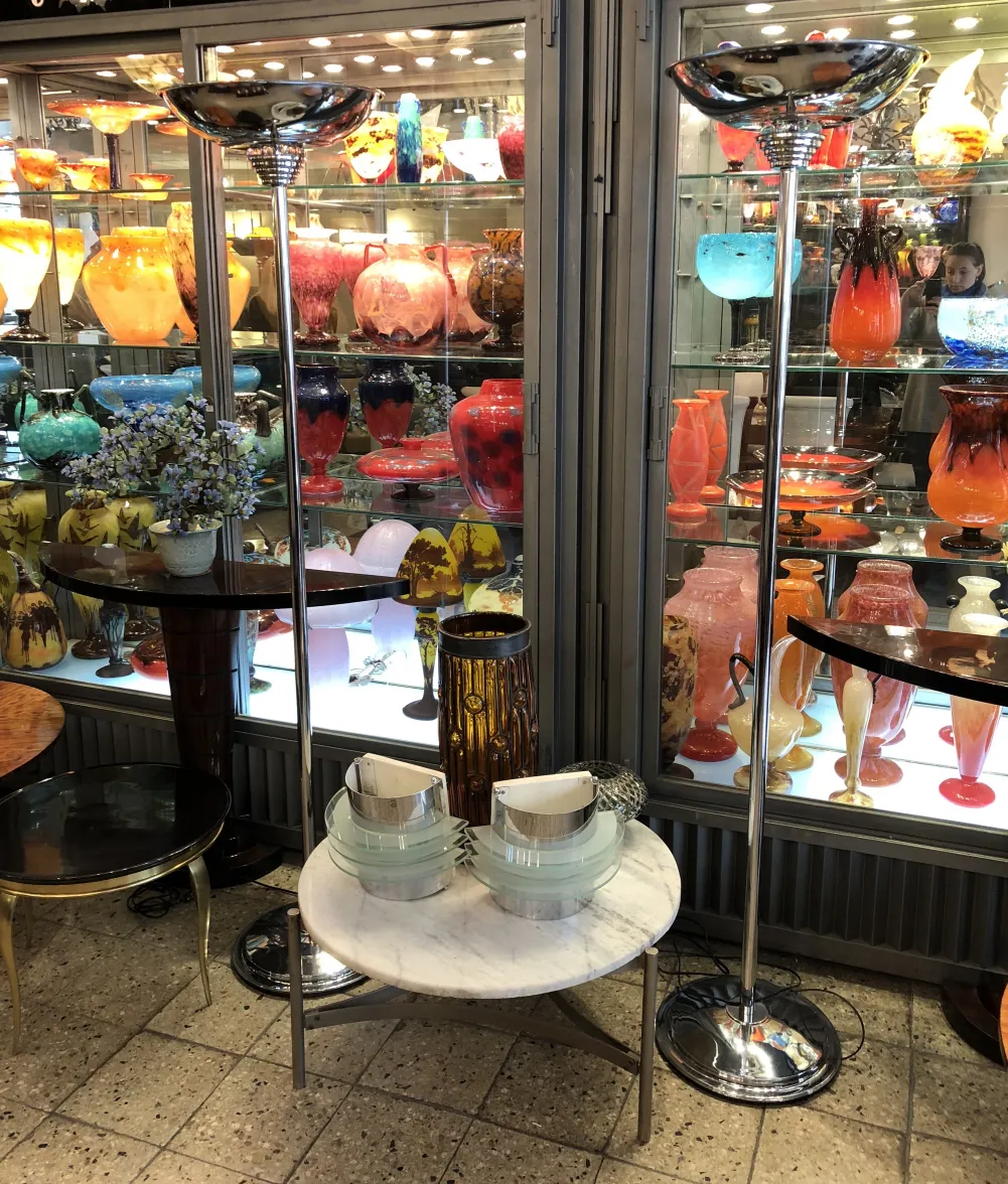 duas elegantes lâmpadas de piso antigas em frente a uma vitrine decorativa de cerâmica