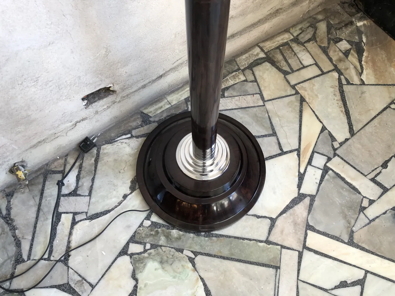 2 antique floor lamps placed in a room with stone flooring.