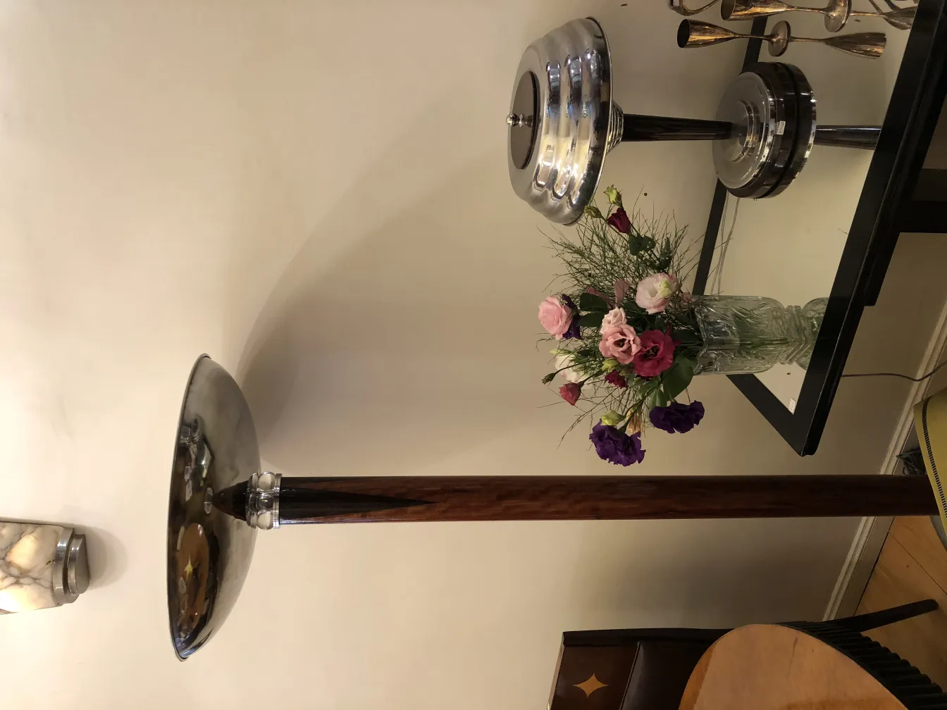 Two antique floor lamps with an elegant design next to a vase of flowers.