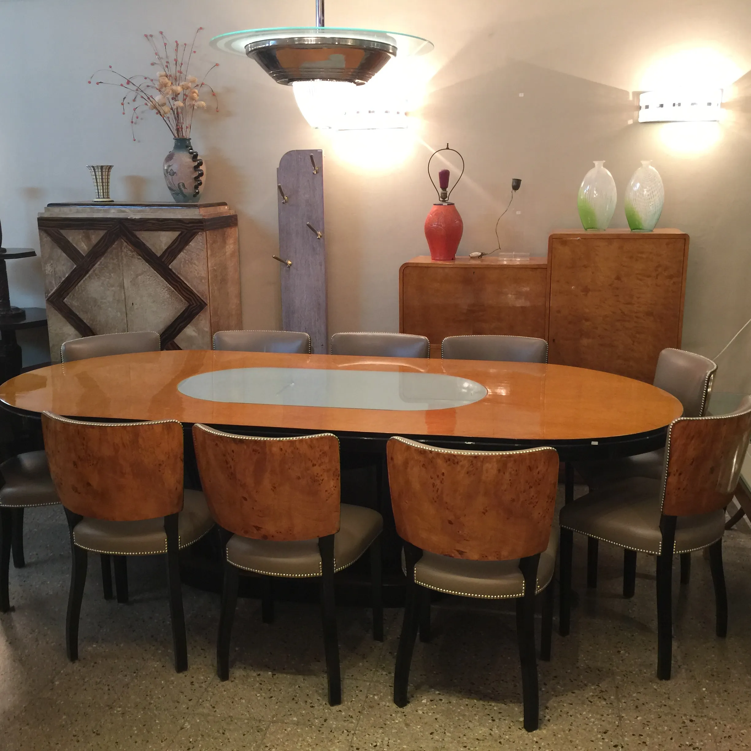 Table de dining ovale antique avec lumière pour 10 personnes, accompagnée de chaises décoratives dans un cadre élégant.