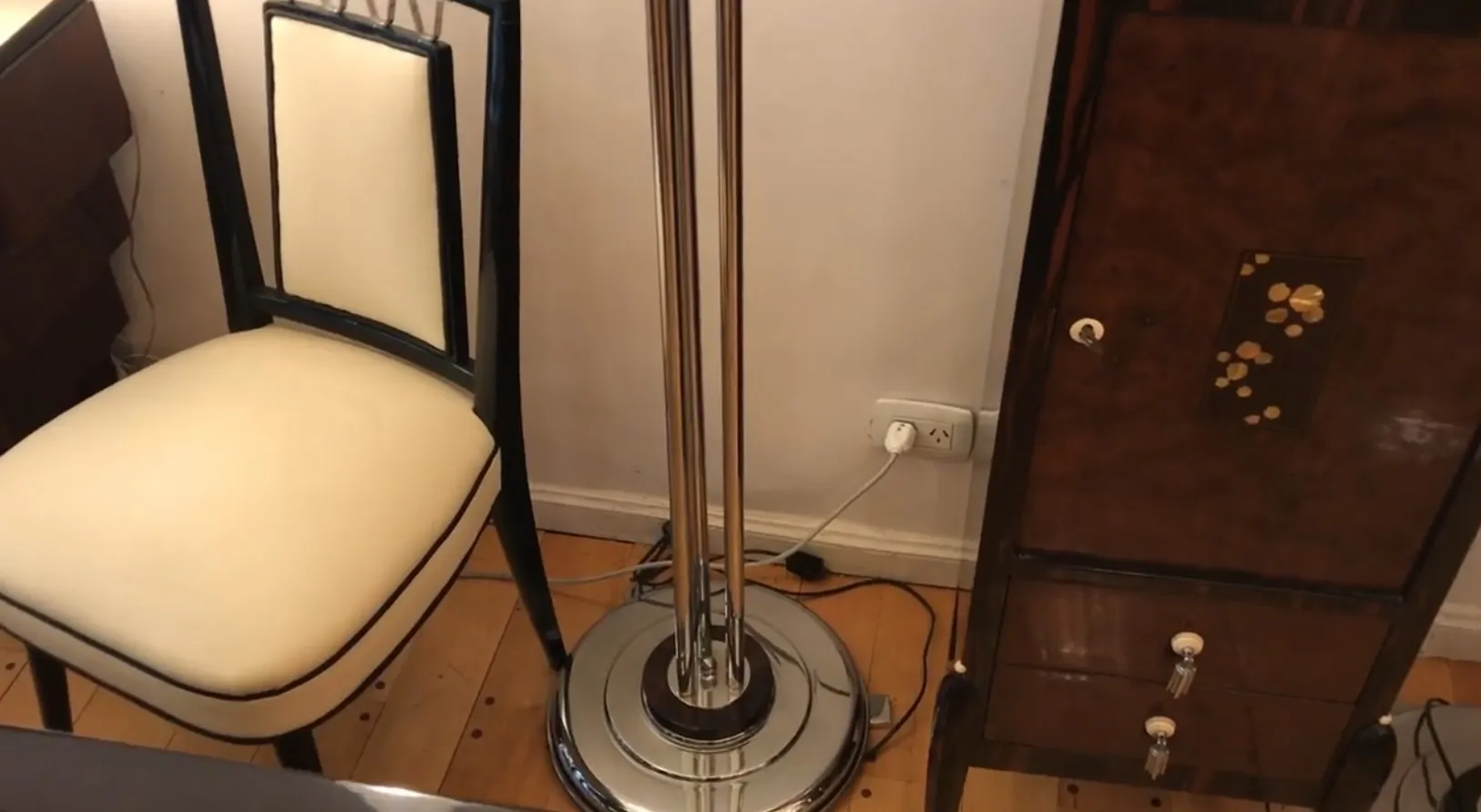 Vista de dos lámparas de pie antiguas junto a una silla y un mueble elegante