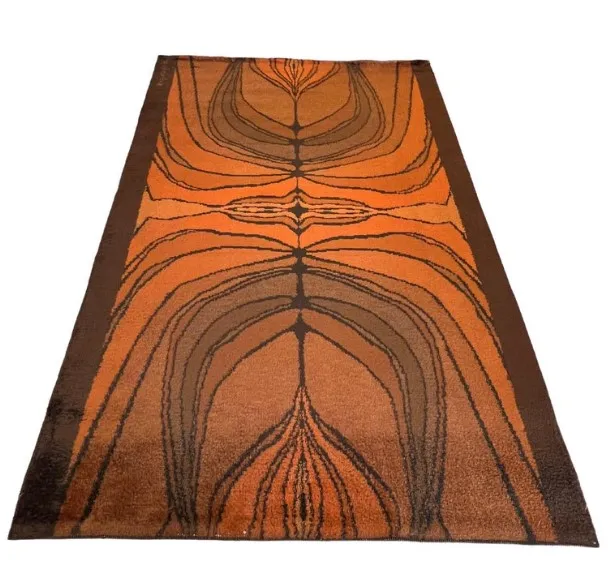 Tapis ancien dans des tons oranges et bruns avec un design abstrait.