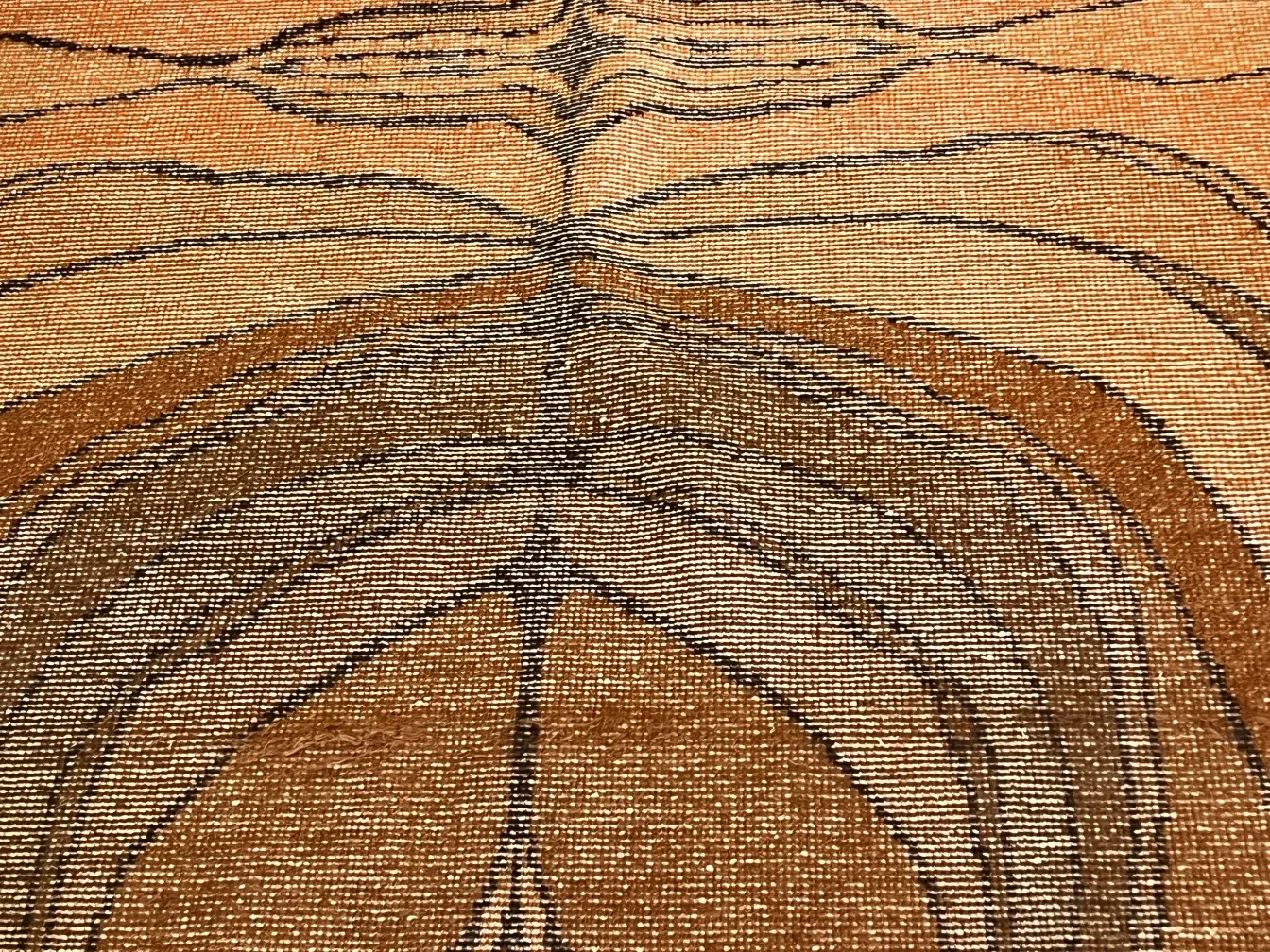 Tappeto antico con design astratto in toni marroni.