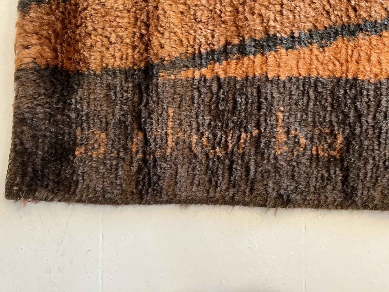 Détails d'un tapis ancien décoratif avec des motifs marron et orange.