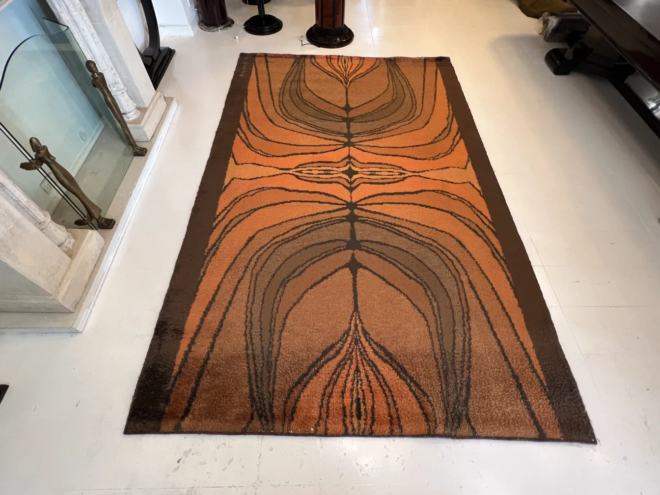 alfombra antigua con patrón en naranja y marrón, en un ambiente acogedor