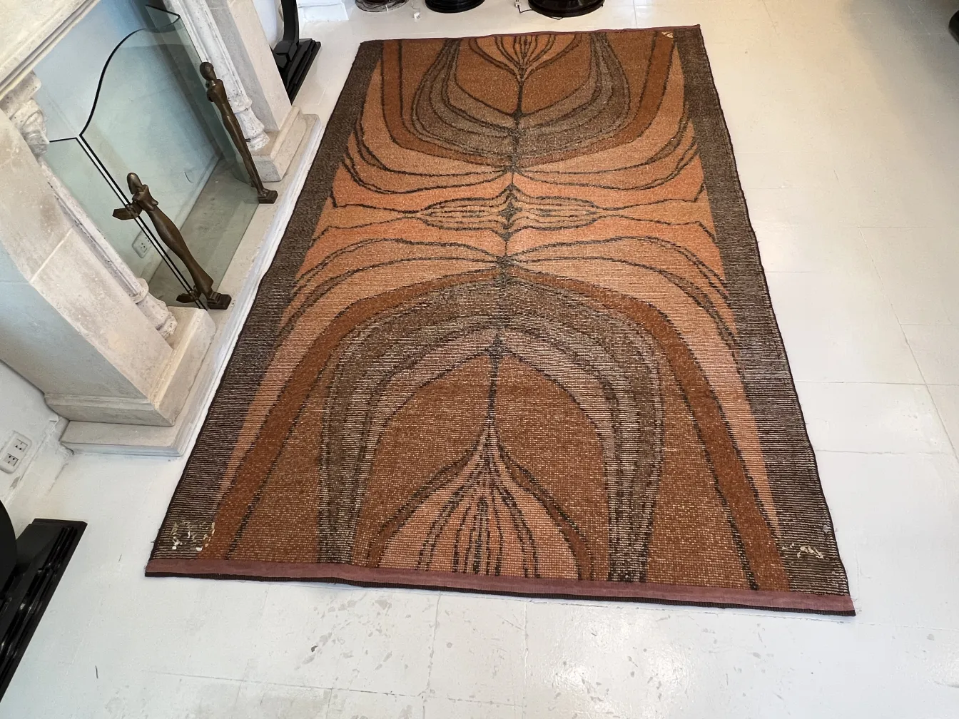 Alfombra antigua con diseño orgánico en tonos marrones y beige, en un ambiente acogedor.