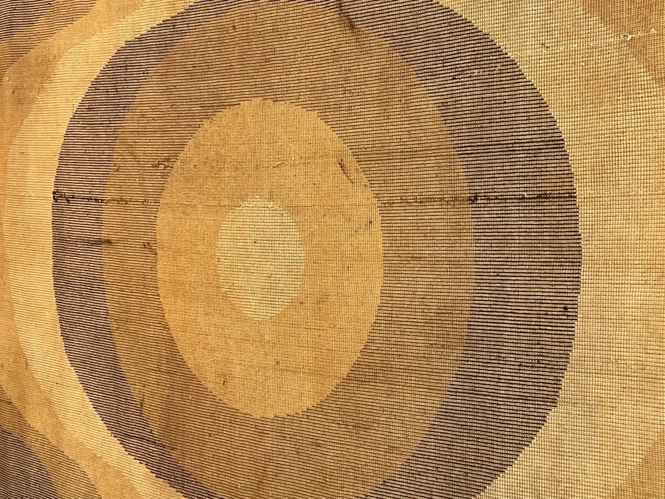 tapis ancien avec des motifs circulaires et des lignes brunes