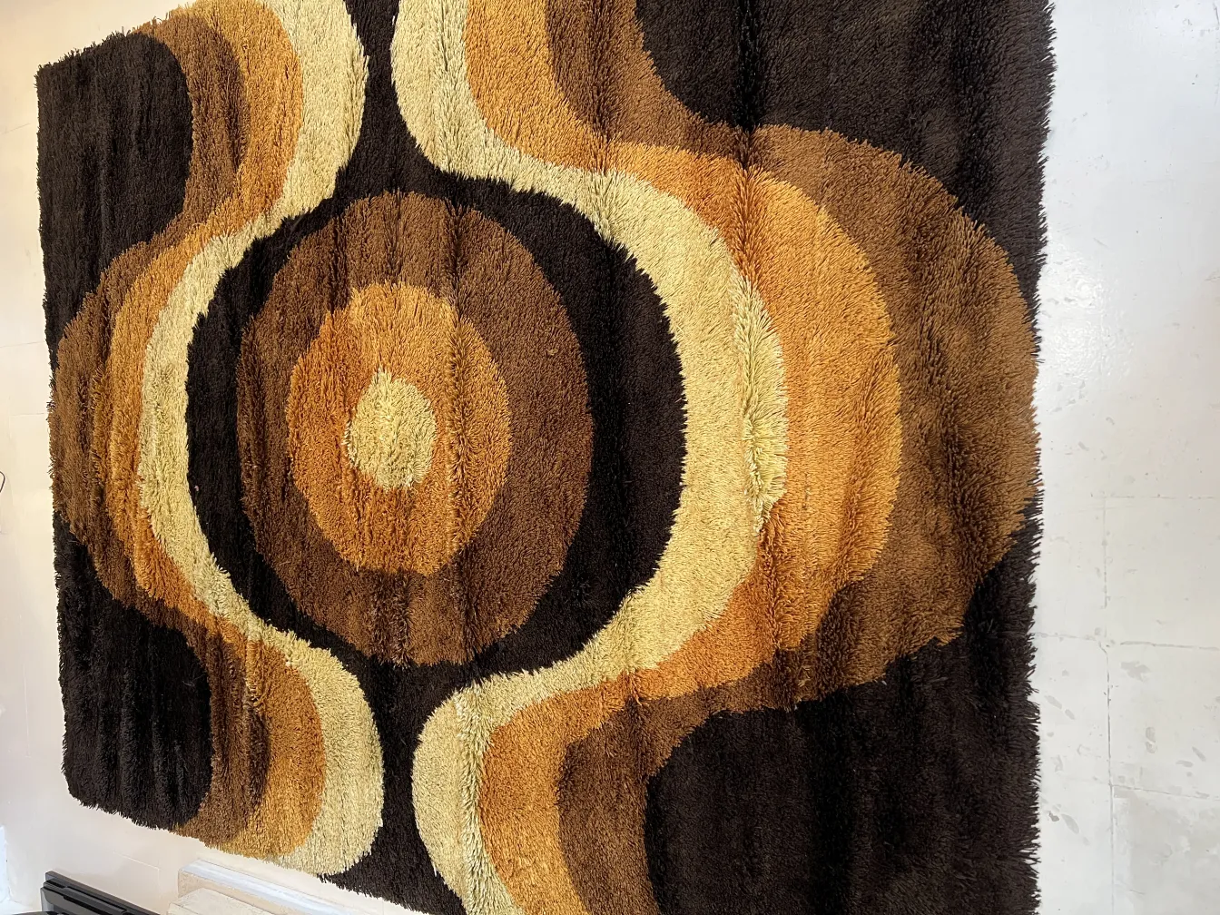 tapis ancien aux tons bruns et beiges avec des motifs circulaires