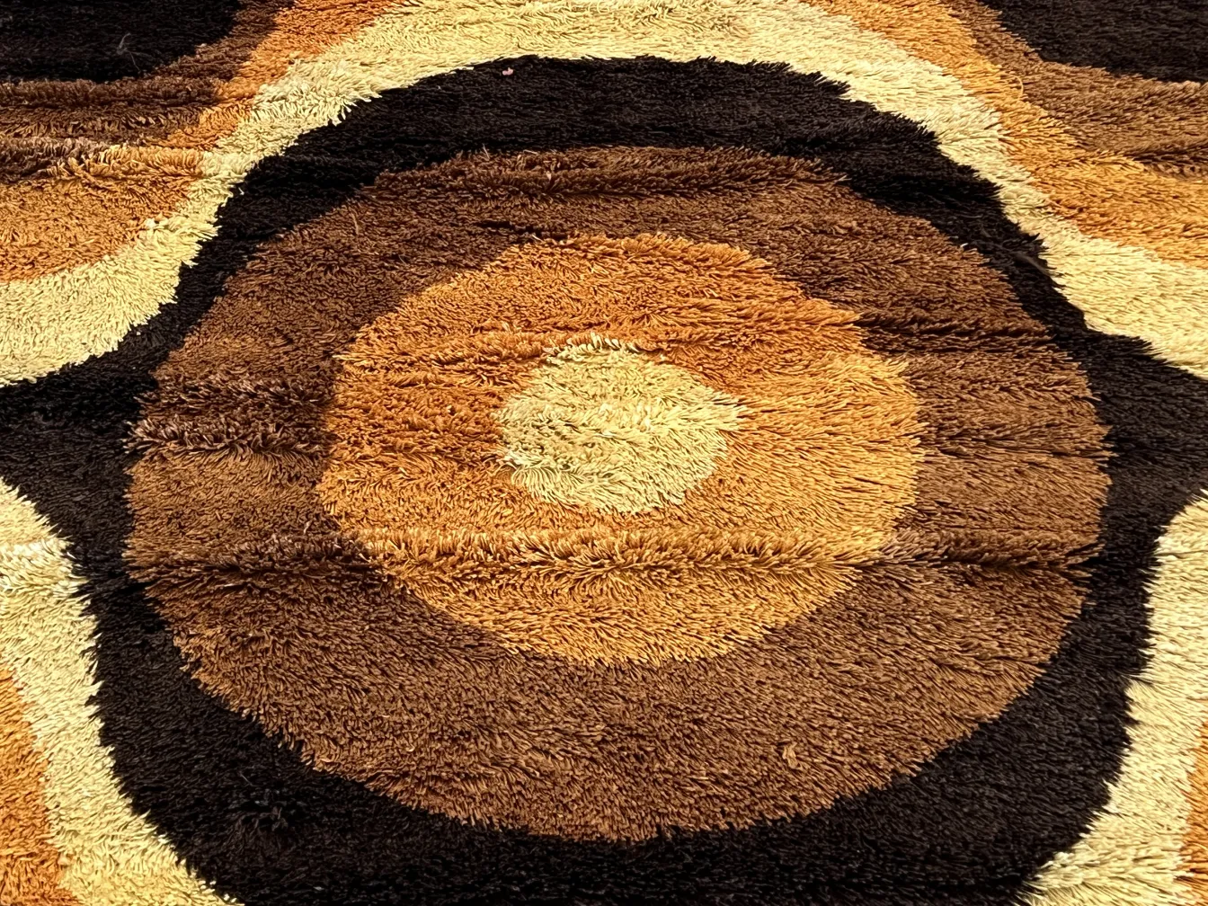 Antique carpet featuring a circular pattern in brown tones