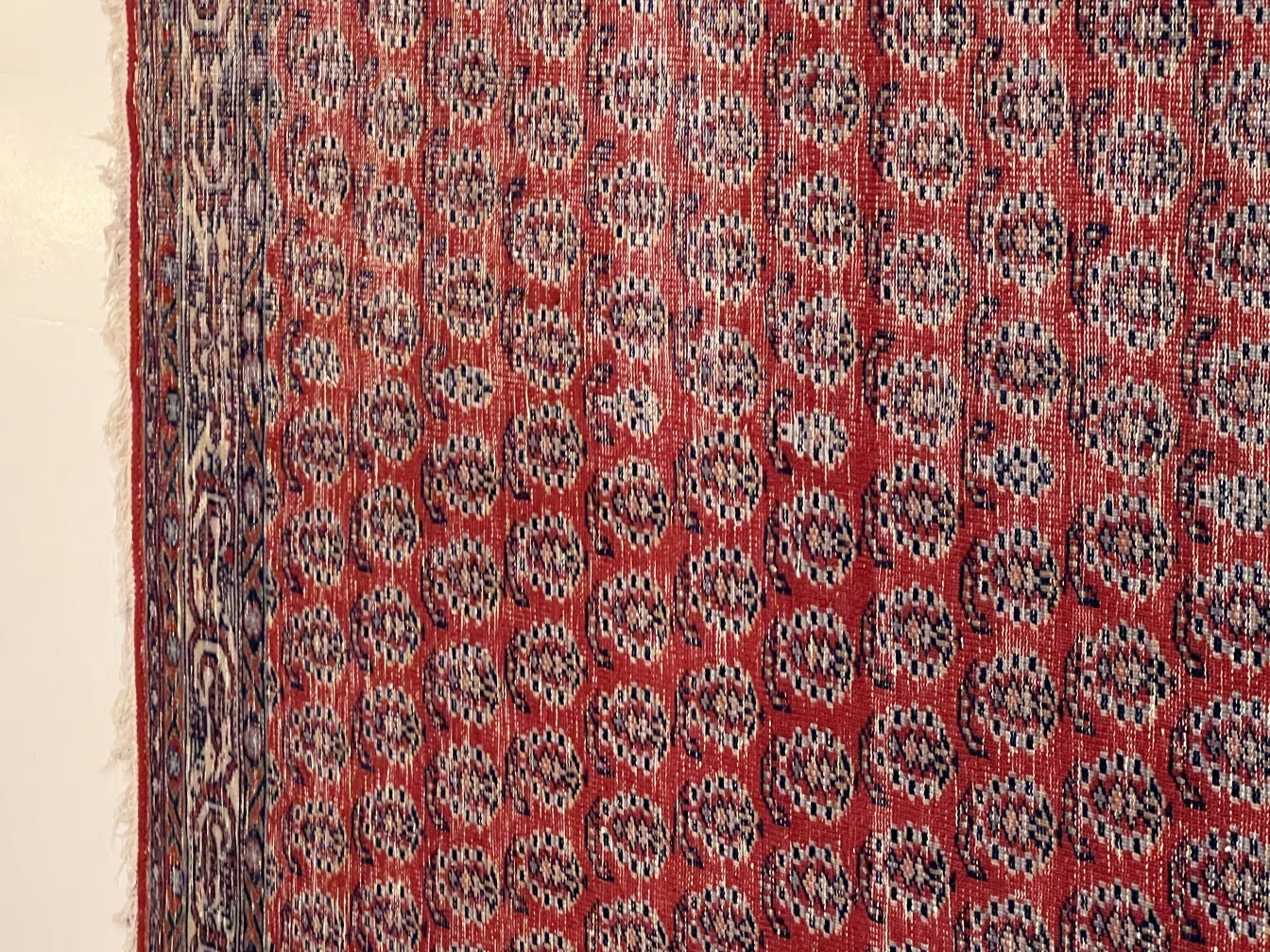 tapis ancien en tons rouges avec un design géométrique proéminent, ambiance chaleureuse