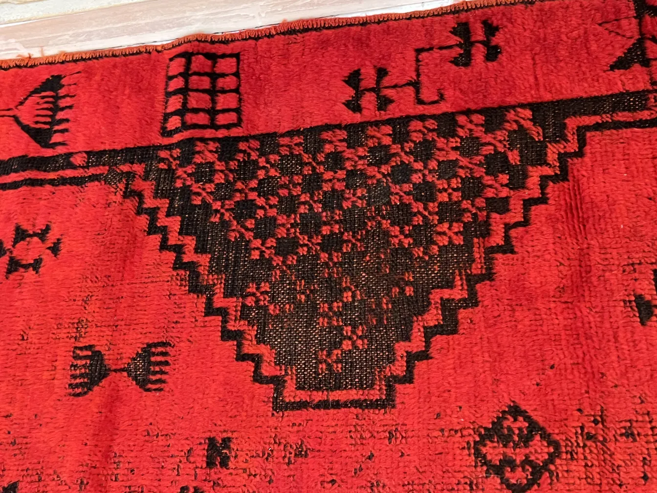 Tapis ancien rouge avec motifs noirs, décoratif.