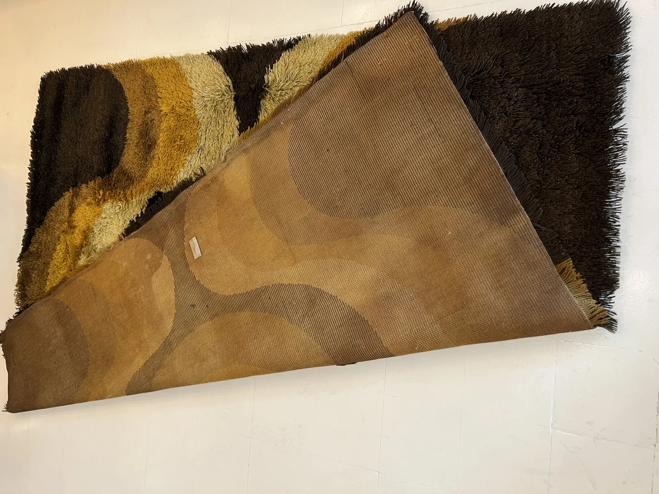 Tapis ancien avec des motifs colorés dans des tons de marron et de jaune.