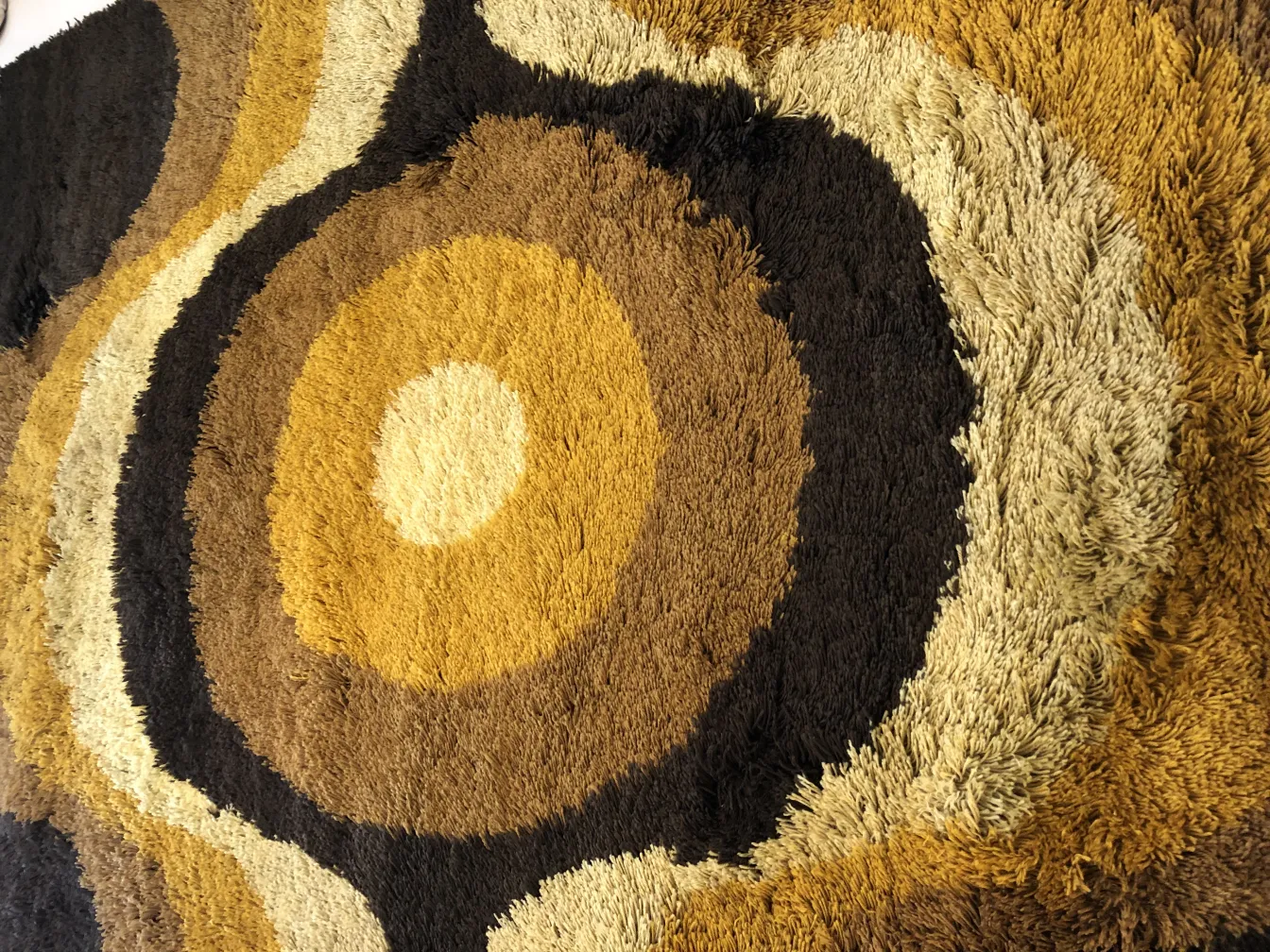 Tapis ancien avec des motifs circulaires en tons terre.