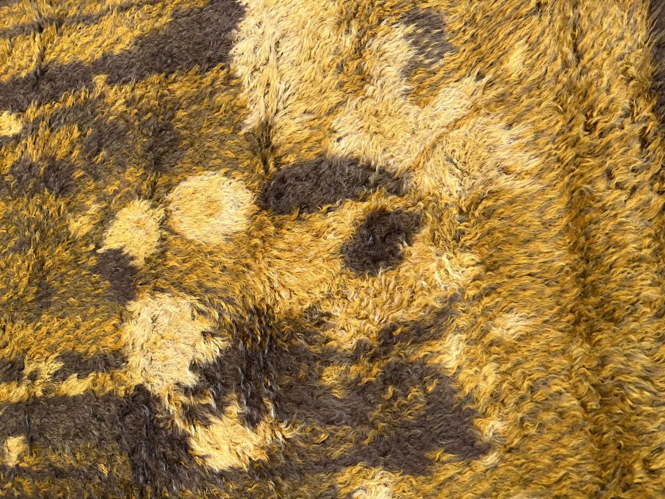 Antiker Teppich mit braunen und gelben Mustern, weiche Textur.