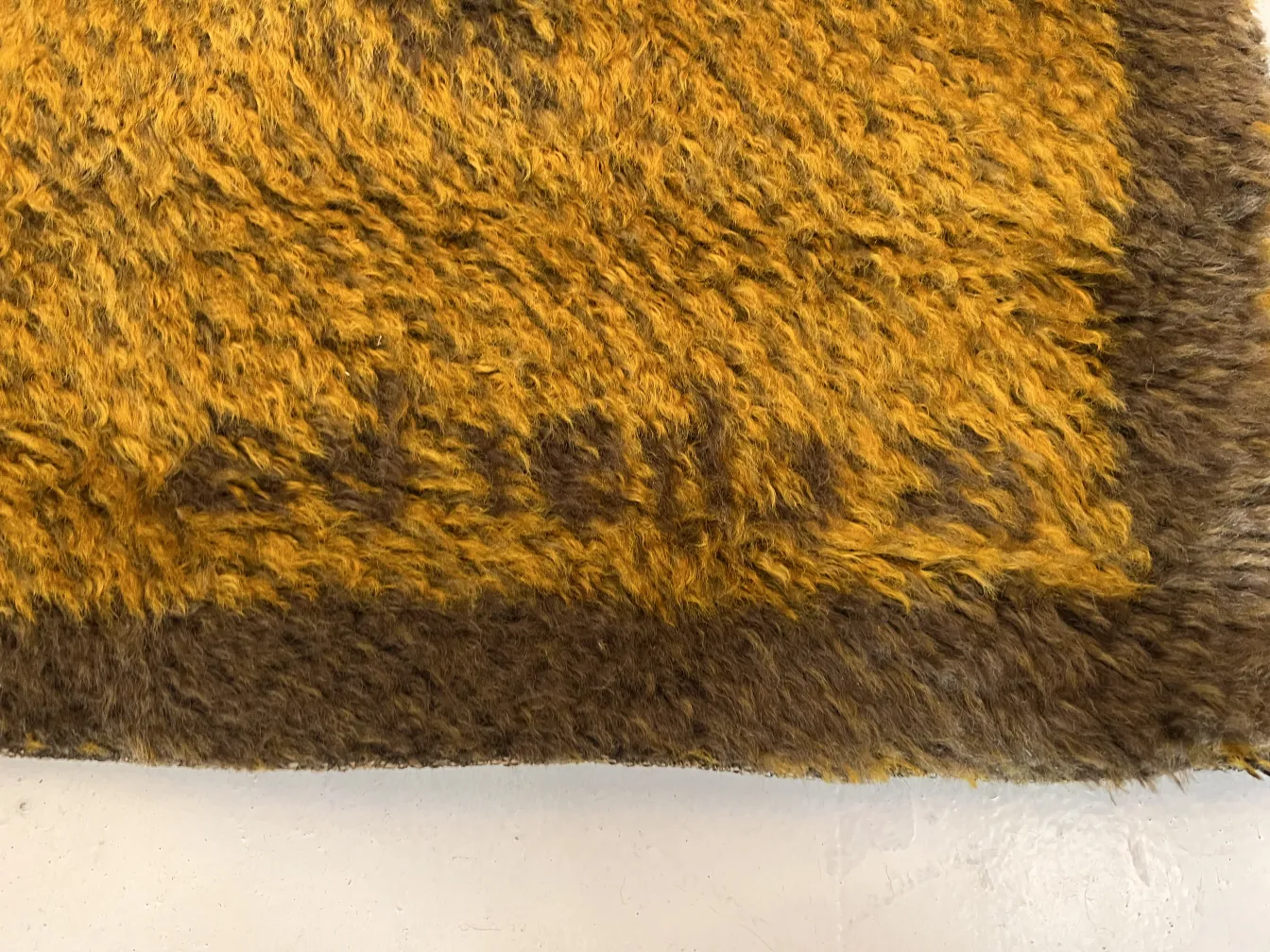 Antiker Teppich mit sanften Gelbtönen und flauschiger Textur