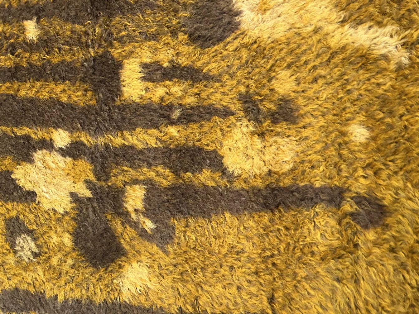 Alfombra antigua con diseños en tonos cálidos y texturas suaves.