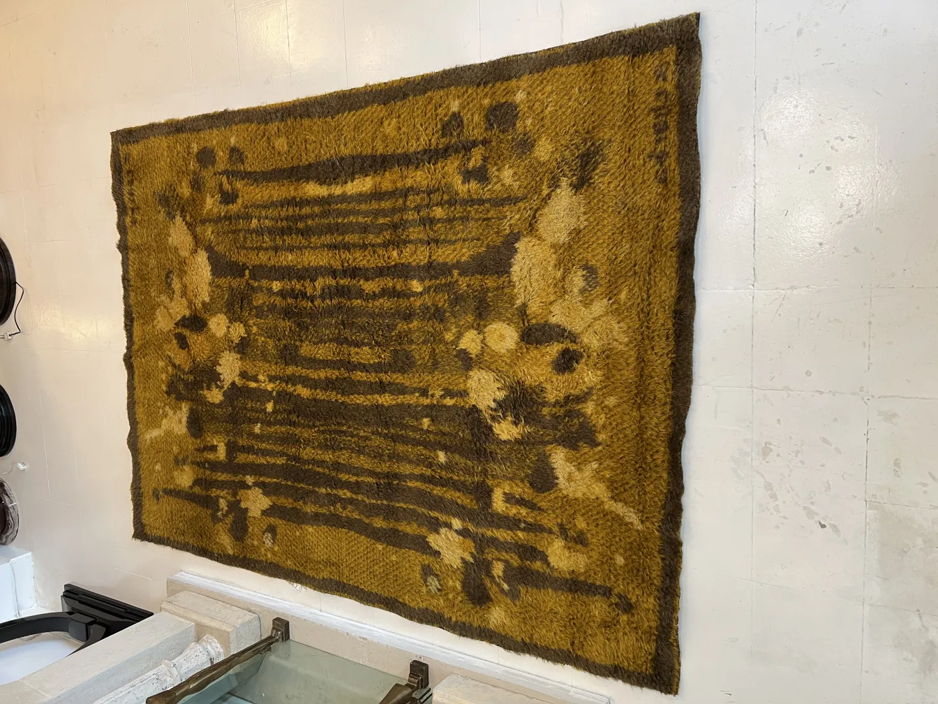 Tappeto antico decorativo di colore ocra su una parete bianca