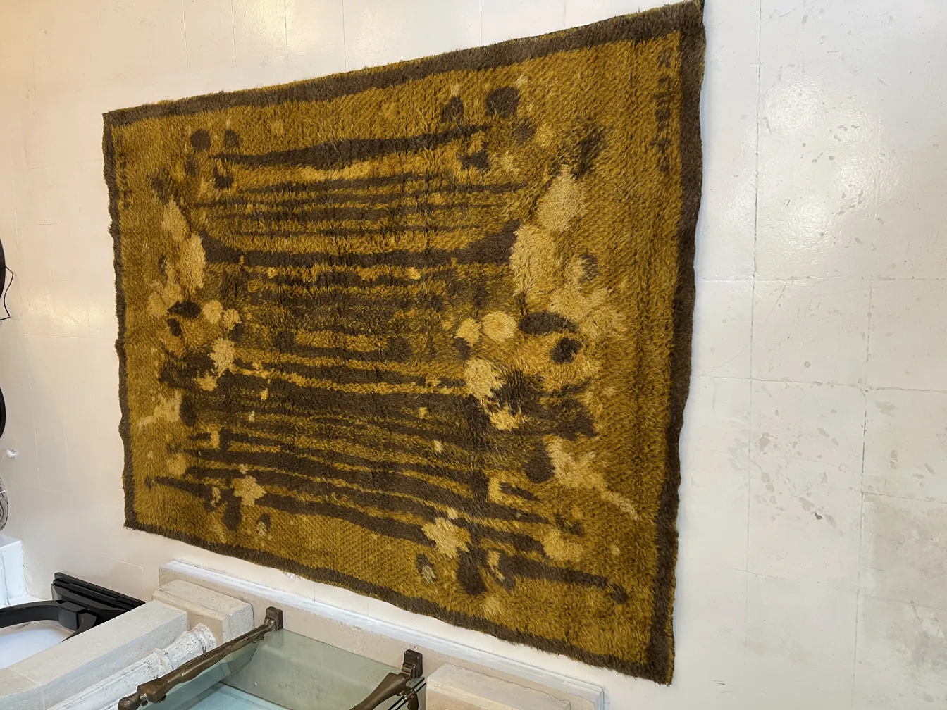 antique carpet with brown and yellow patterns in a neutral setting