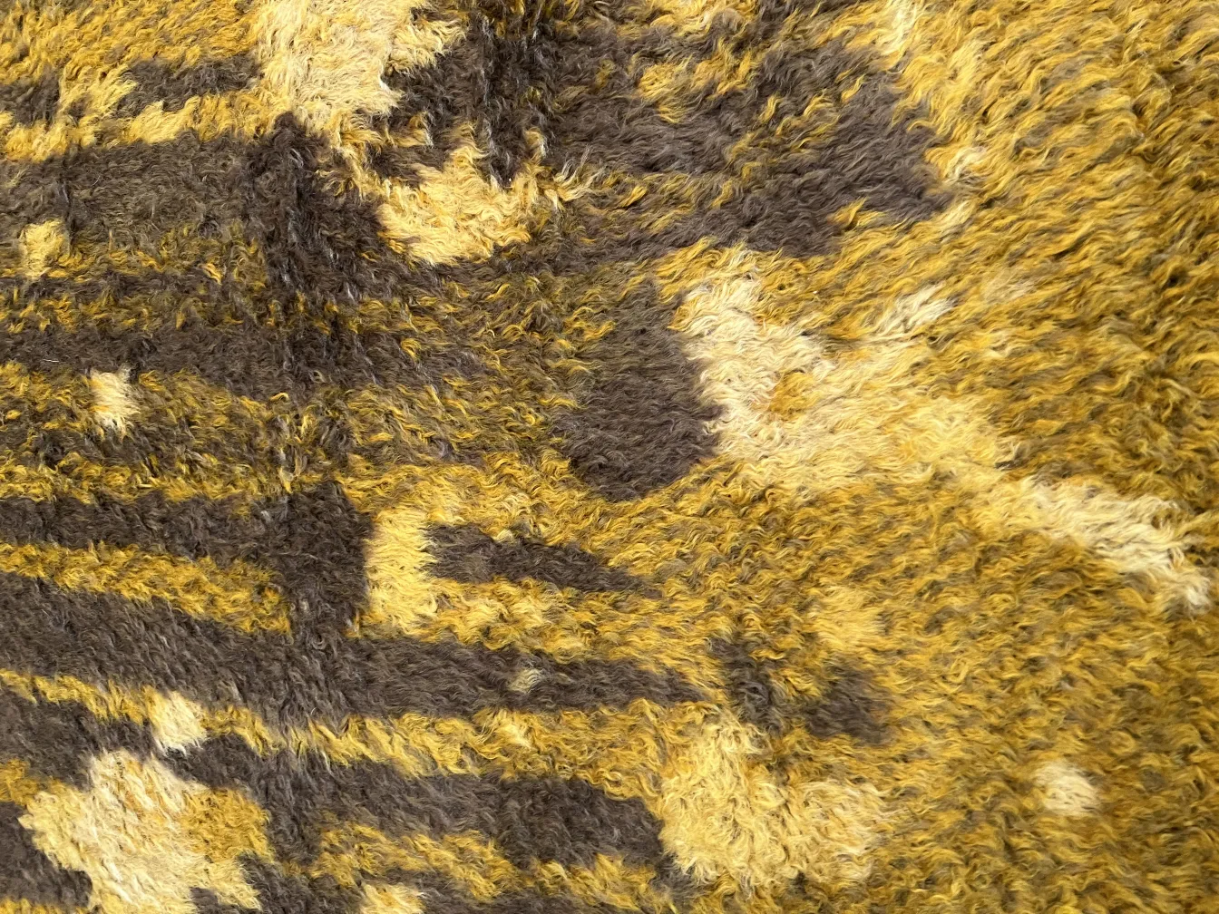 Antiker Teppich mit sanften gelben und braunen Texturen.