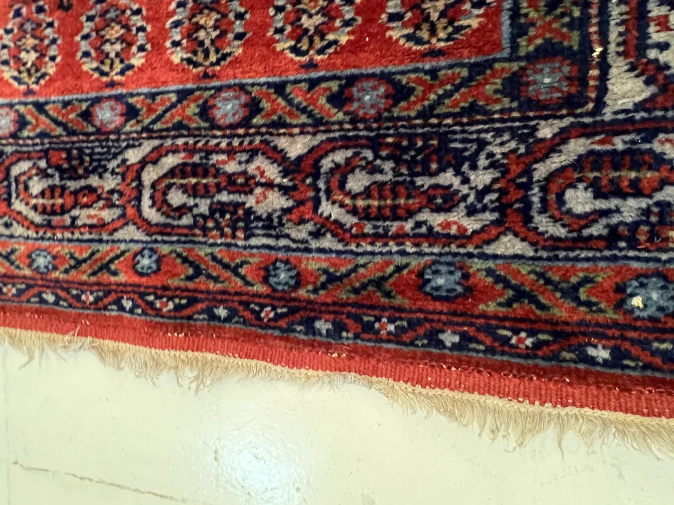 tapis rouge avec des motifs traditionnels et des franges dorées