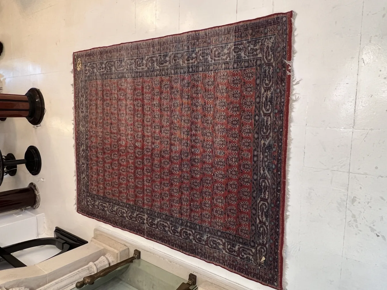 antique carpet in red and blue hanging on a white wall, featuring traditional patterns