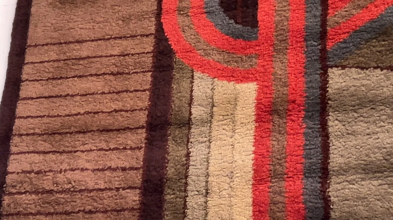 tapete antigo com cores marrons, vermelhas e desenhos abstratos em um ambiente moderno