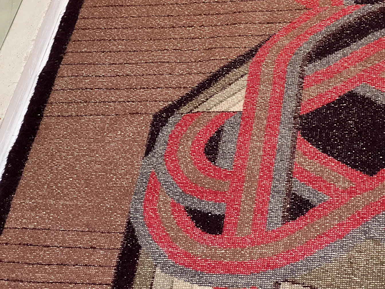 Tapis ancien avec des motifs géométriques dans des tons neutres.