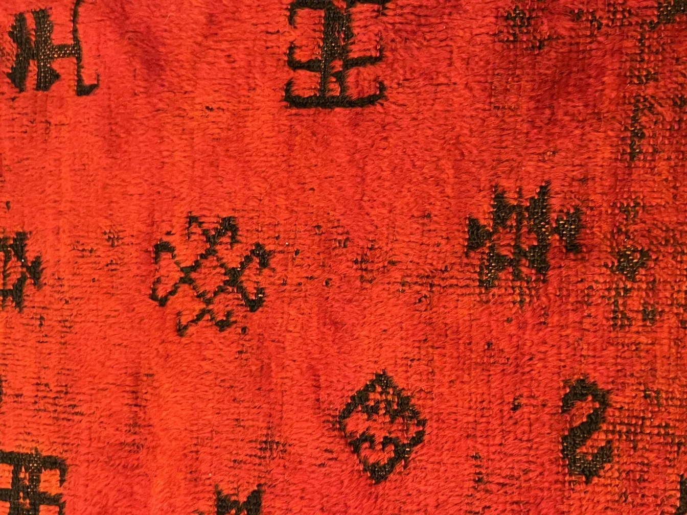 Alter roter Teppich mit dekorativen Mustern und Symbolen